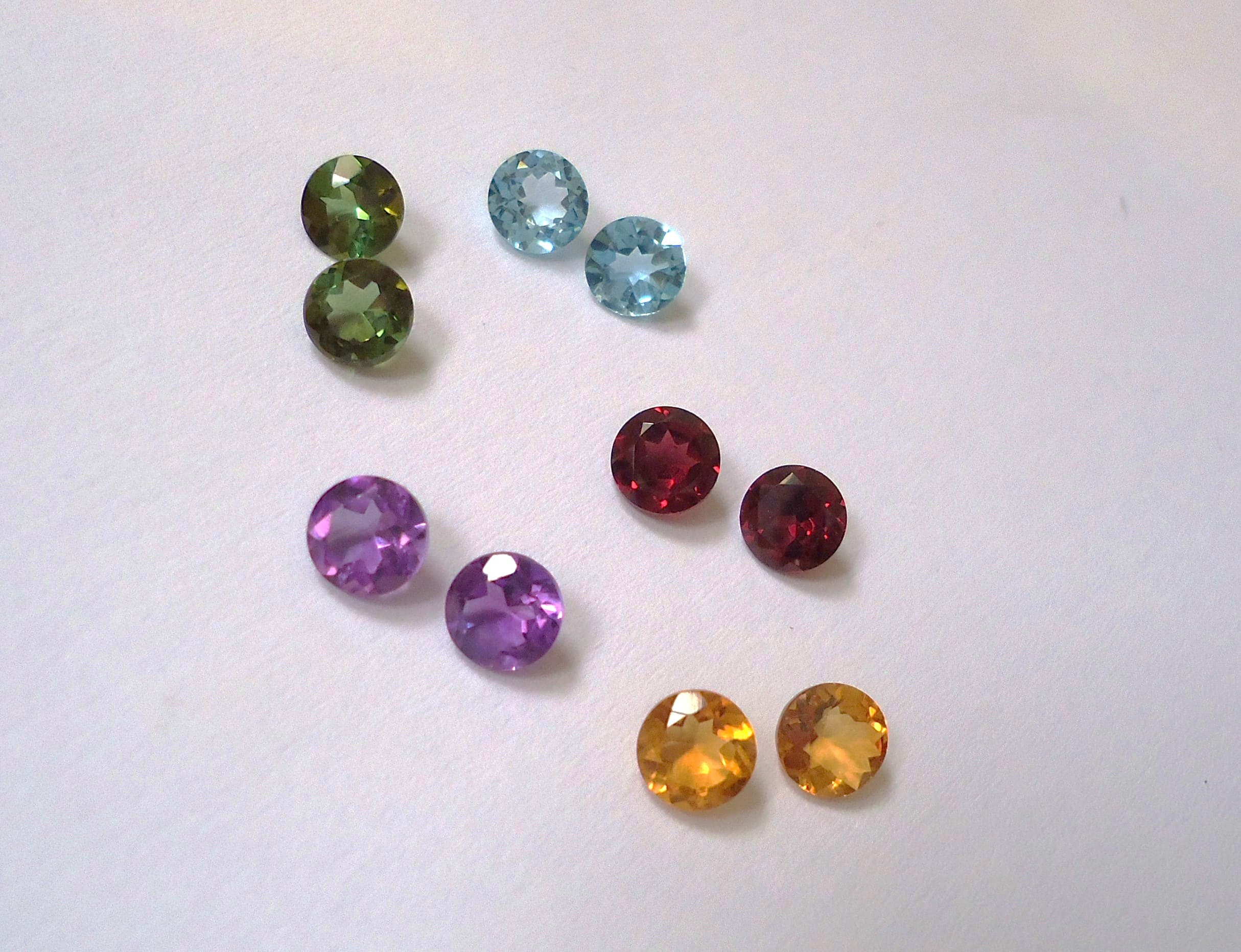 Loose blue and green gemstones arranged on a neutral cloth